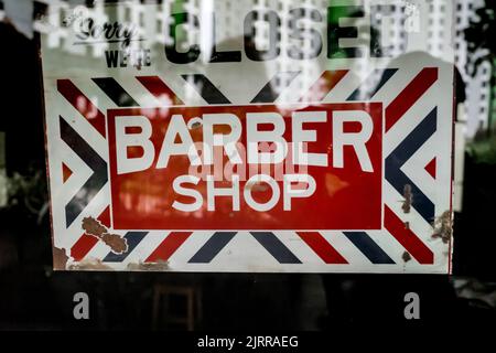 Closed door sign on a barber shop glass door. Red white navy sorry we`re closed door sign hanging on a barber shop front glass door Stock Photo